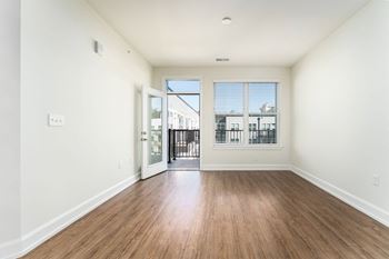 a living room with a hard wood floor and a door to a balcony
